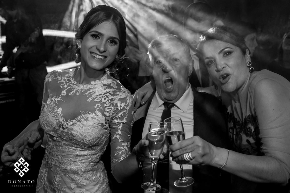 Noiva com o tio e a mãe, fazem um brinde muito alegre.