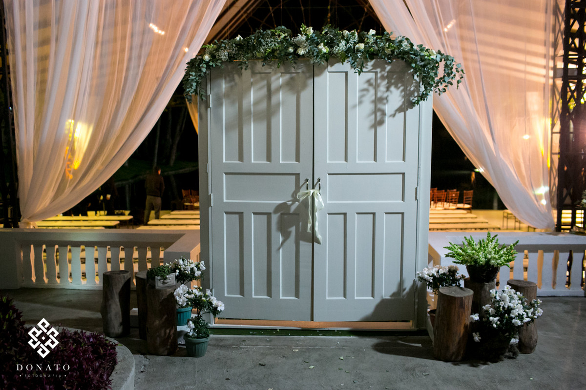 detalhe da porta branca, com arranjos, na entrada da nave da fazenda 7 lagoas.