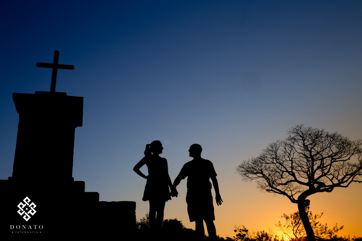 Foto em silhueta dos noivos entre a cruz e uma arvore seca, foto linda.