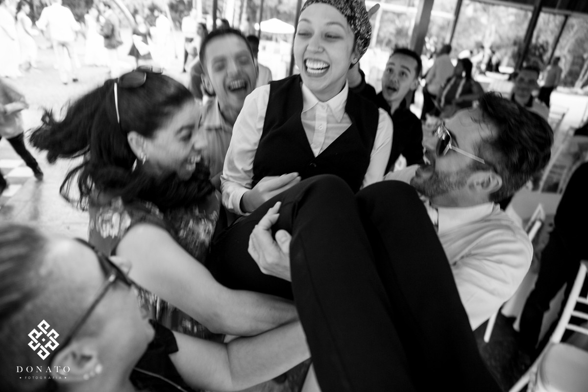 Convidados jogam a garçonete pra cima, a imagem é muito divertida e alegre.