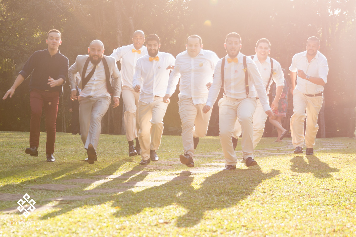 Padrinhos correm com uma luz amarelada ao fundo, imagem bem divertida.