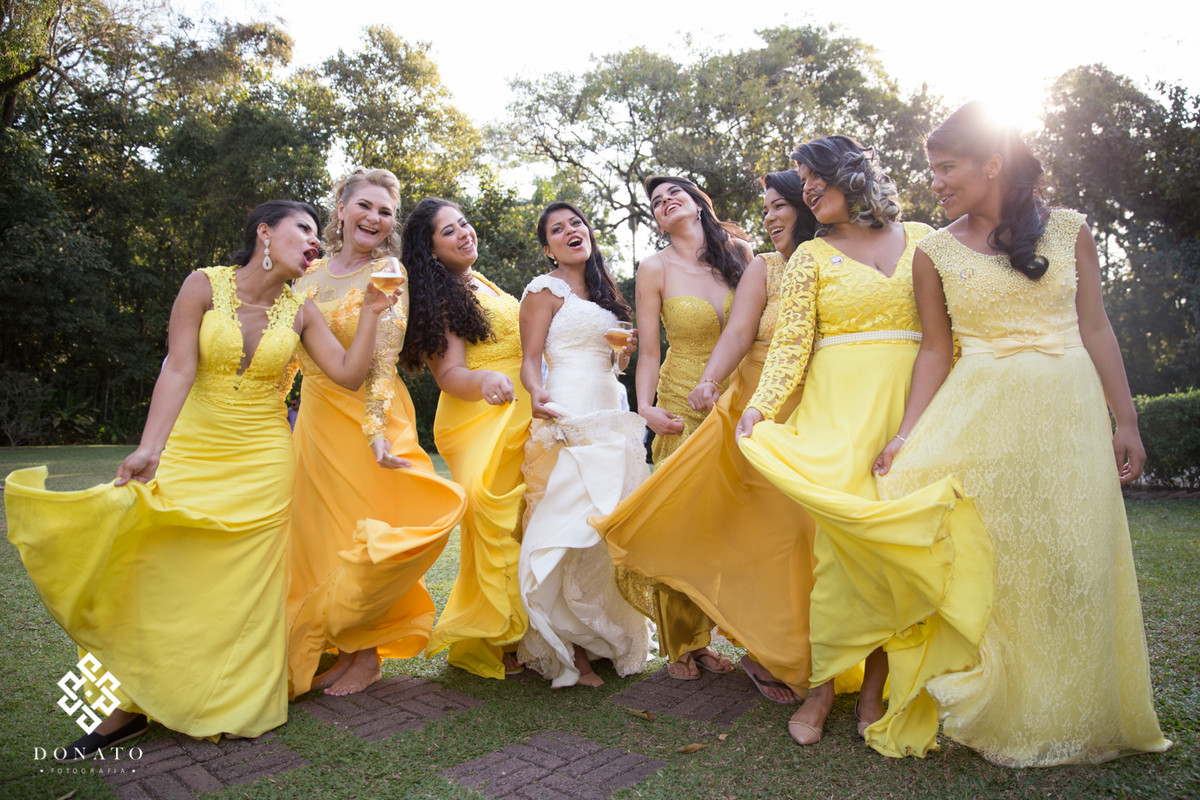 A noiva e as madrinhas brincam com o vestido, todas as madrinhas com vestidos amarelos deixa um efeito bem legal a imagem.
