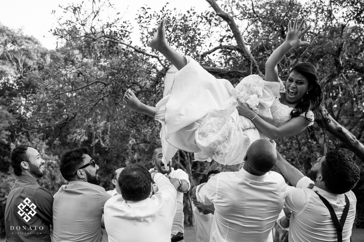 A noiva é jogada pra cima, ela esta de lado e muito alegre, congelado no ar, paresse que o tempo parou e ela esta flutuando na alegria.