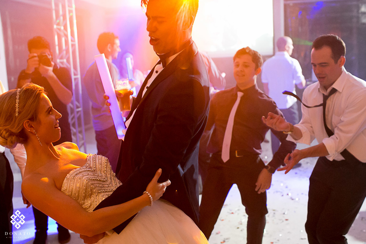 noivo dança com a noiva, com uma luz meio alaranjada.