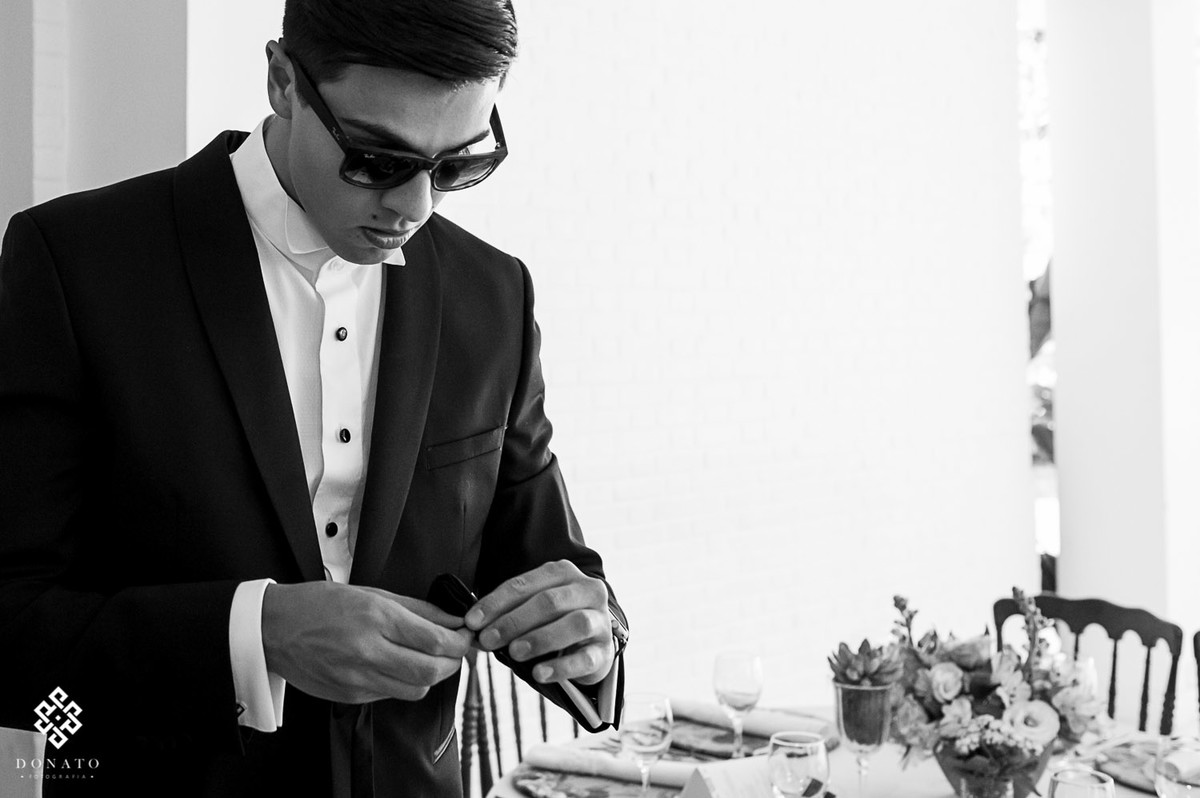 noivo de oculos escuro arruma os detalhes da festa.