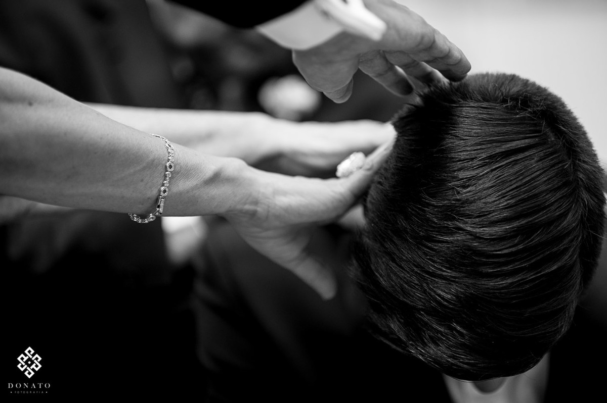 mae e pai colocam a mão na cabeça do noivo, dando sua bençao.
