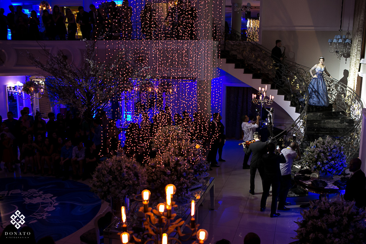 aniversariante desce por escadaria do buffet kristian platz, um veo de luzes deixa tudo mais lindo ainda.