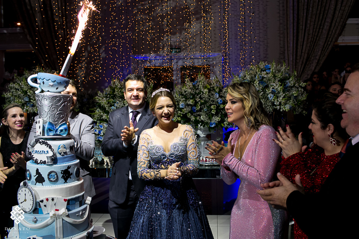 hora do parabéns, a frente o bolo lindo com o tema alice, e ao fundo todos muito animados cantando parabéns.
