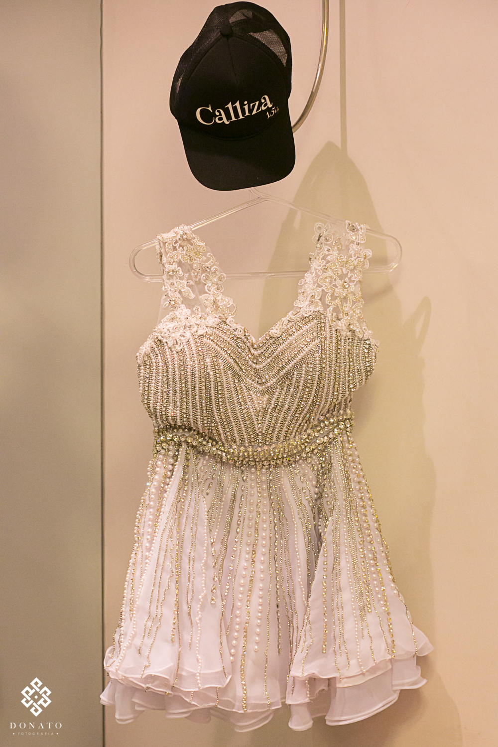 vestido da balada, pendurado em um cabide, junto com um boné personalizado com o nome da debutante.