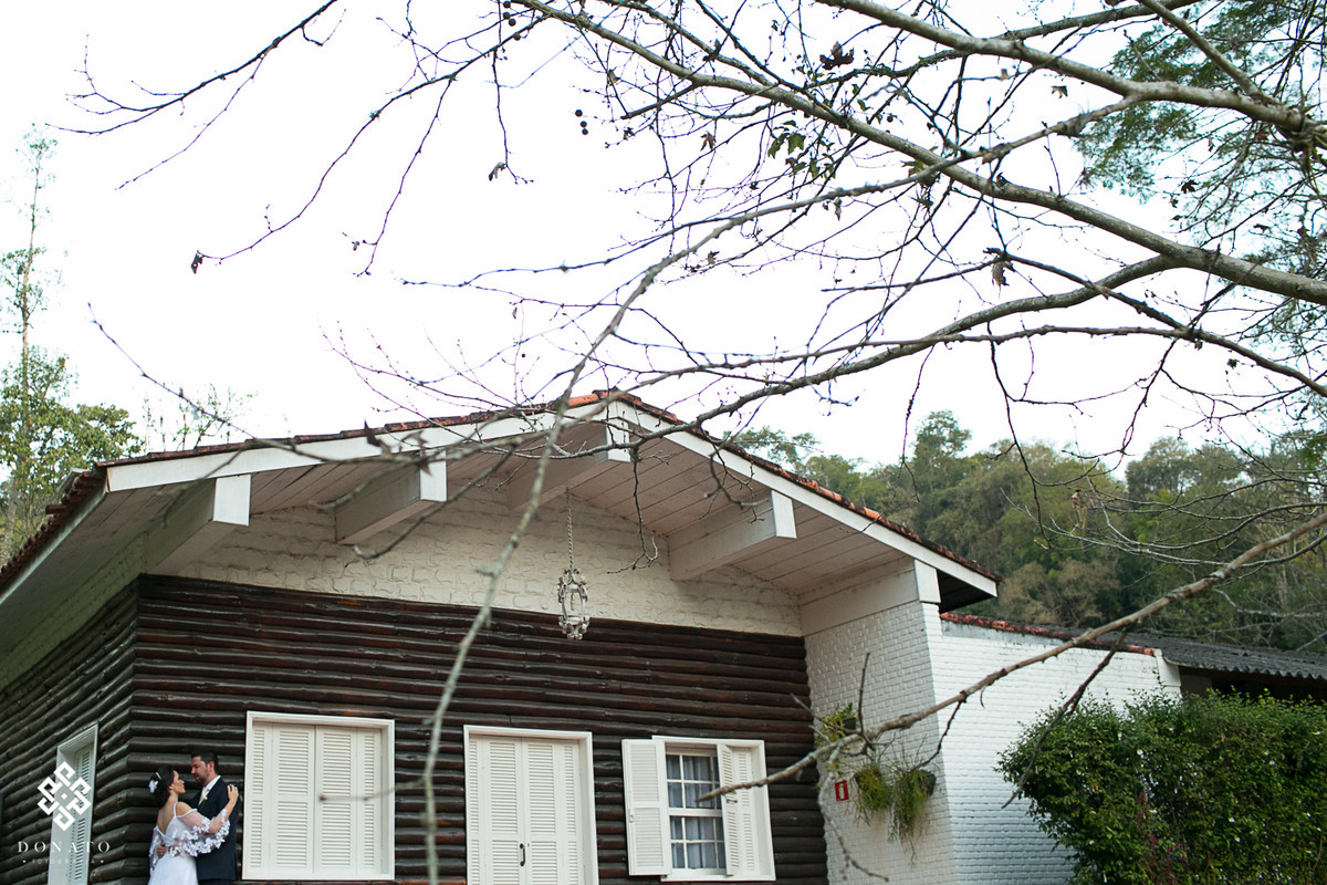 noivos namoram em frente a casa onde a noiva se maqueia e se prepara para o casamento.