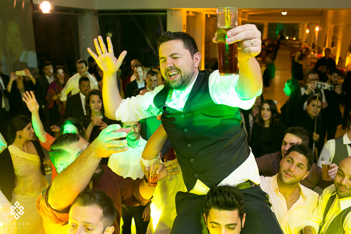 convidados levantam o noivo enquanto a pista de dança esta fervendo na fazenda.
