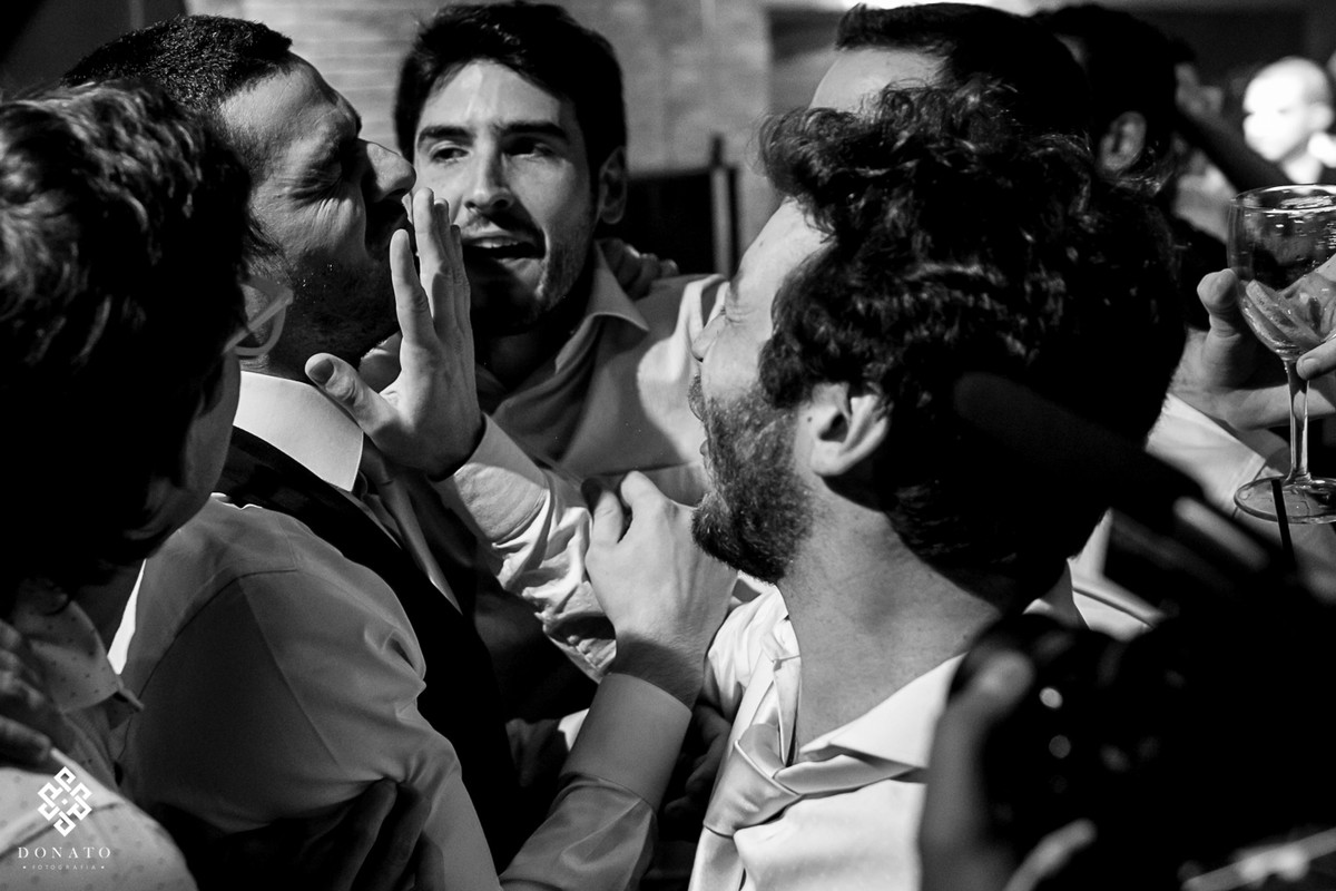 amigos empurão o rosto do noivo em uma brincadeira no meio da balada.