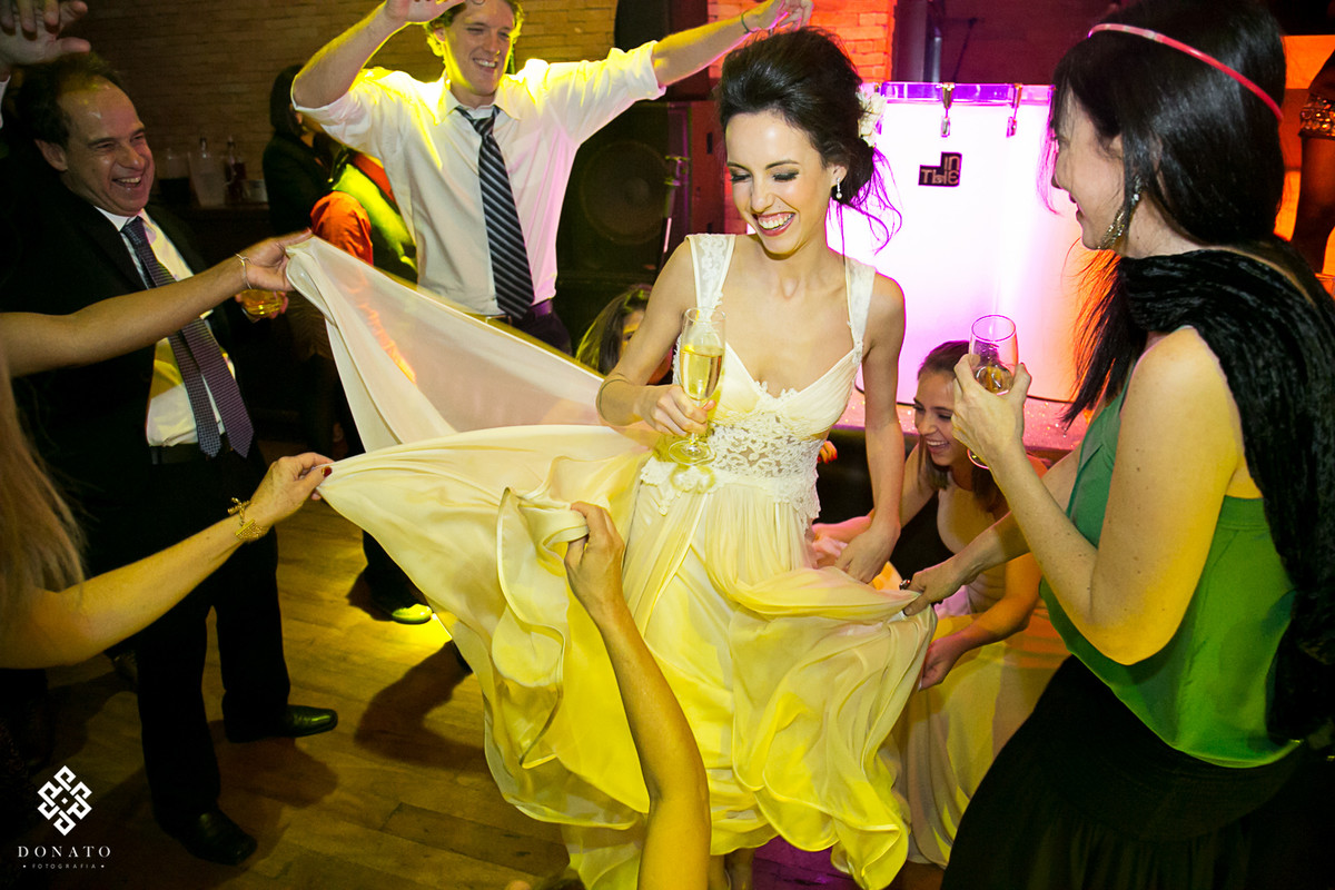 noiva dnaça e amigas pegam nas bordas do vestido lindo feito pela Fernanda Guedes.