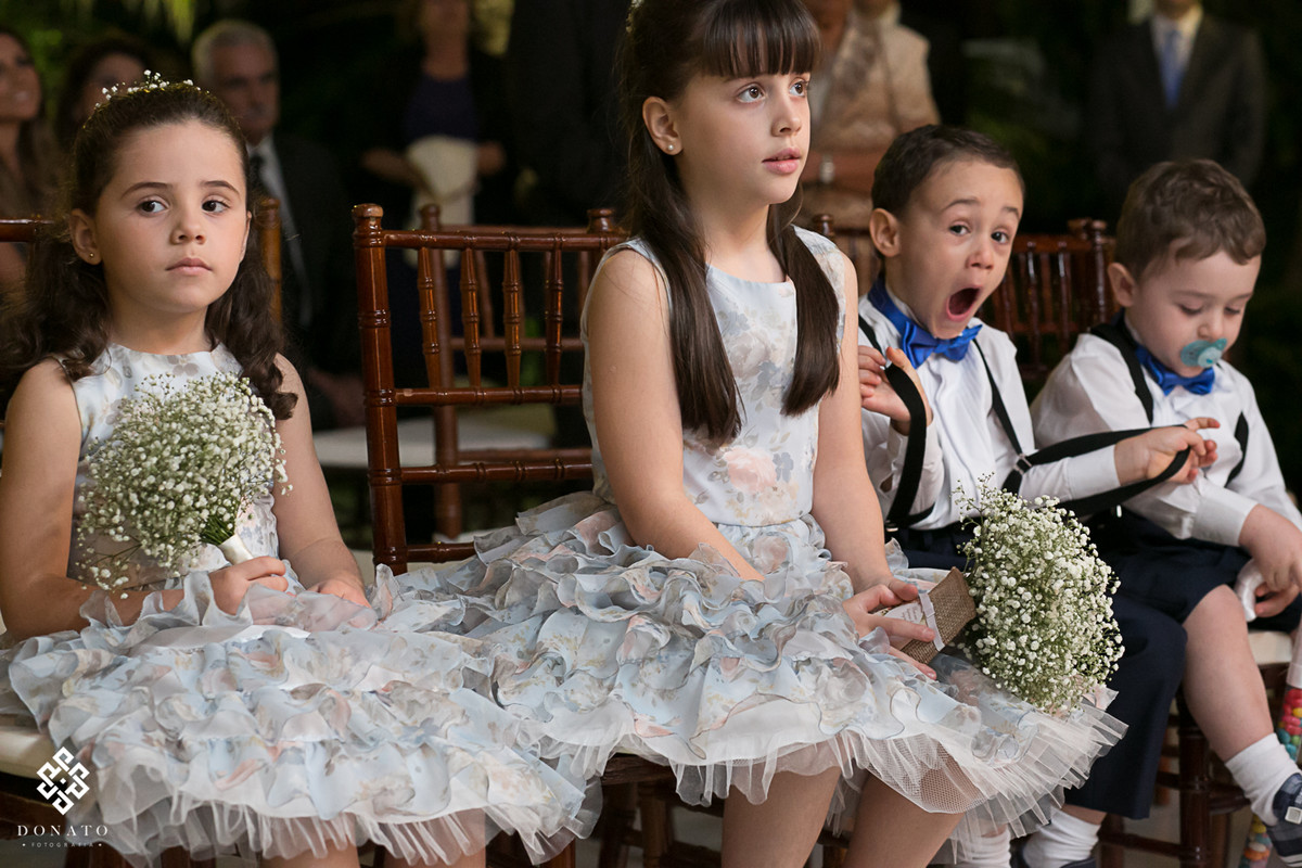 Pajem abre a boca com sono, enquanto as daminhas prestam atenção na cerimonia.