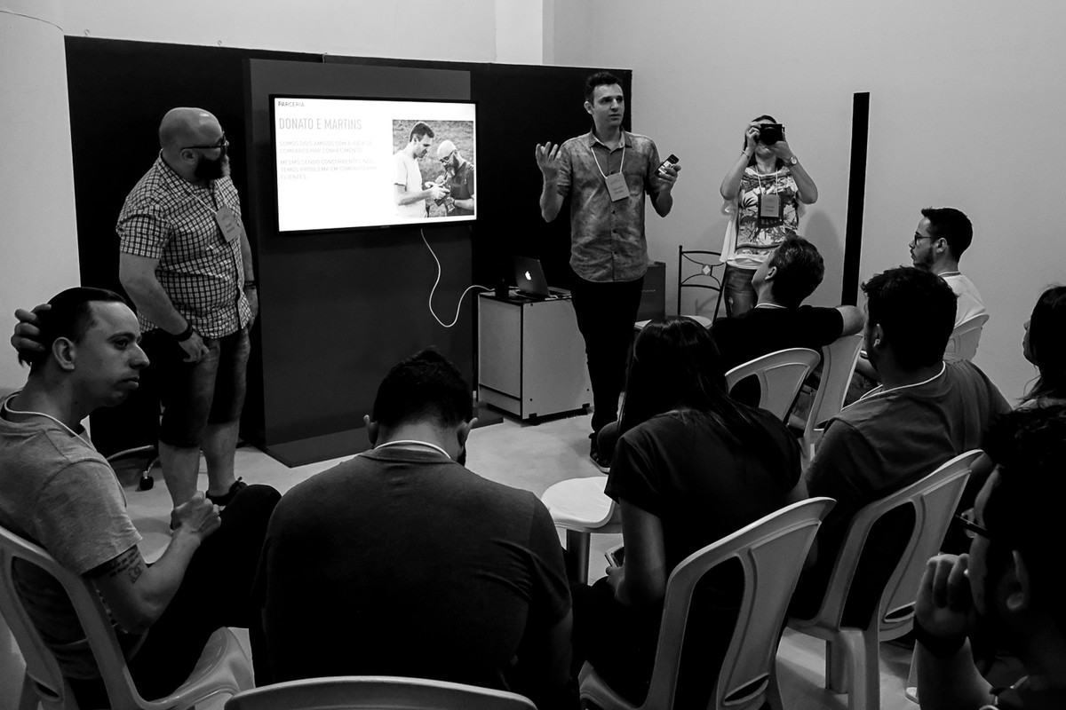 Leandro apresenta enquanto aparece na imagem a Tatiane braga fotografando e o Andre Martins olhando.