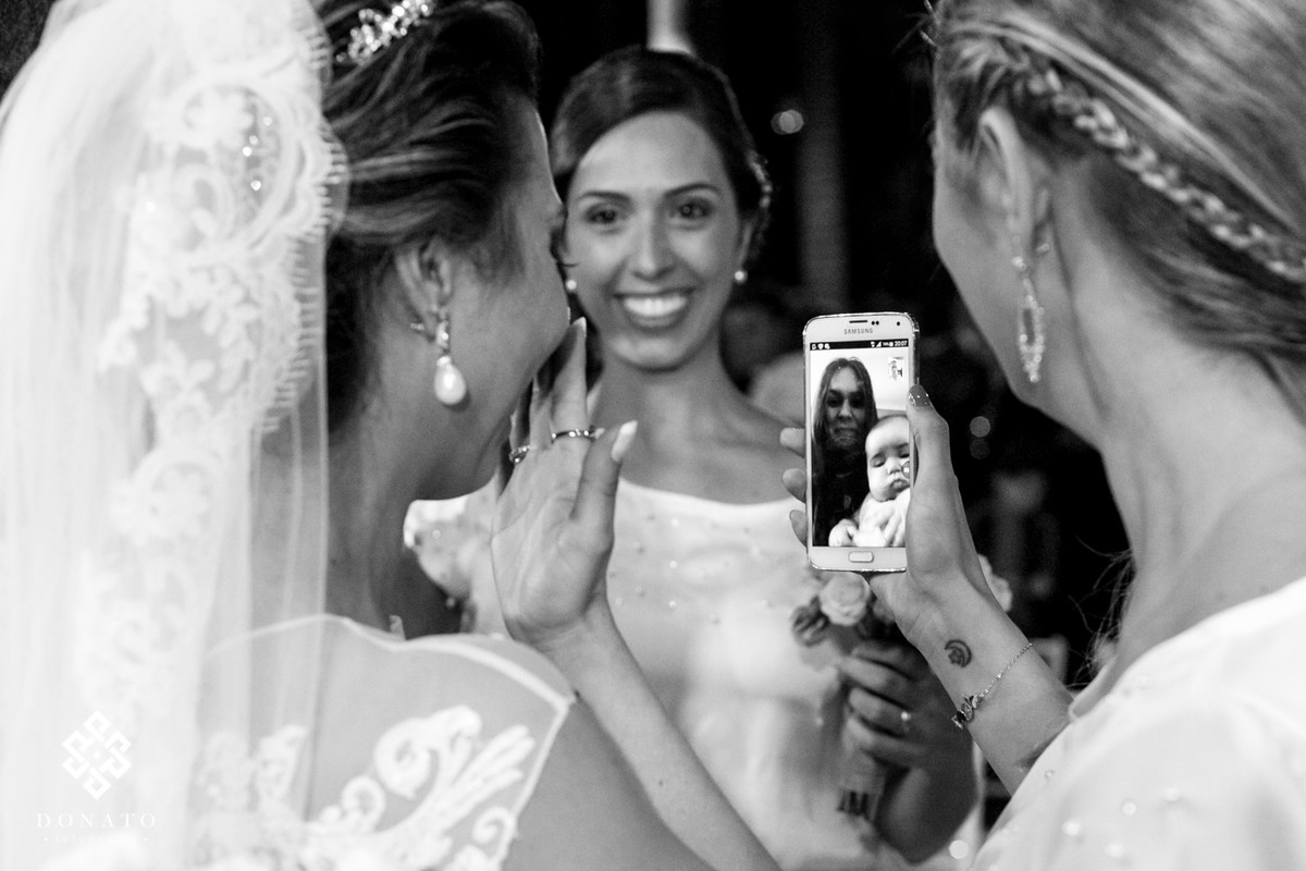 Noiva se emociona ao ver a amiga no celular, a imagem vem dos EUA, via um video chamada.