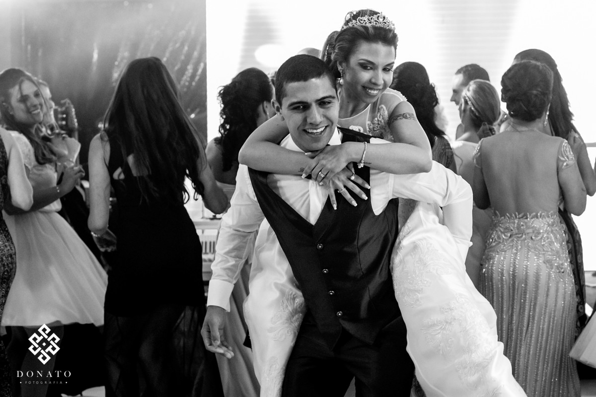 Noiva sai de cavalinho no noivo, os dois se divertem na pista de dança.