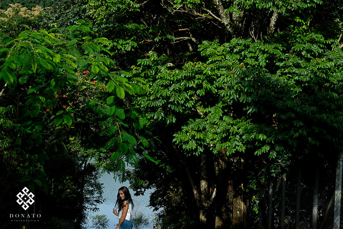 debutante esta emoldurada por arvores e um fundo de um lago azul lindo.