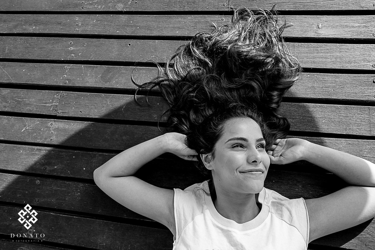 maria victoria esta deitada ao chão, com os cabelos todos jogados no pier de Piracaia.