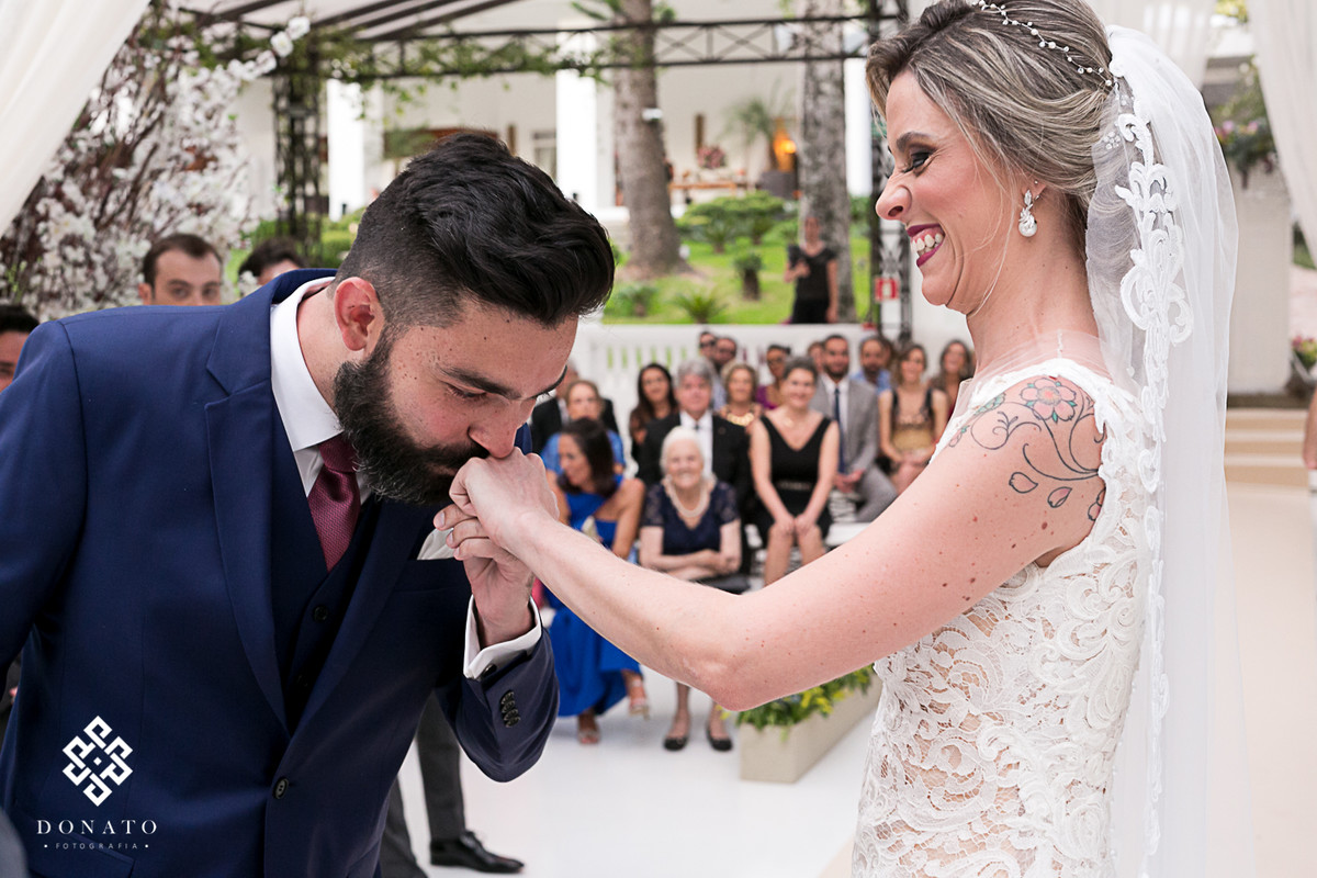 Noivo beija a mão da noiva na troca das alianças.