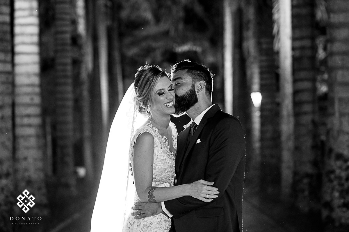 Noivos dao um beijo na entrada da fazenda 7 lagoas entres as enormes palmeiras centenárias.