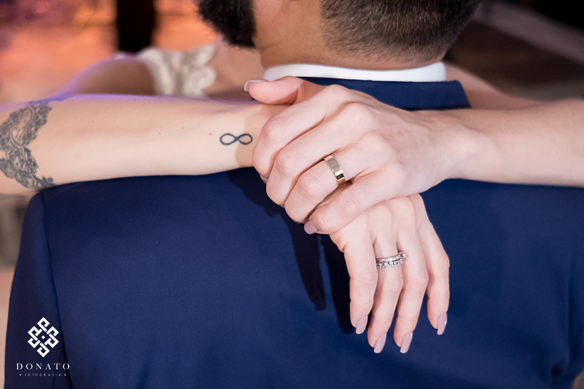 Detalhe das mão da noiva no ombro do noivo.
