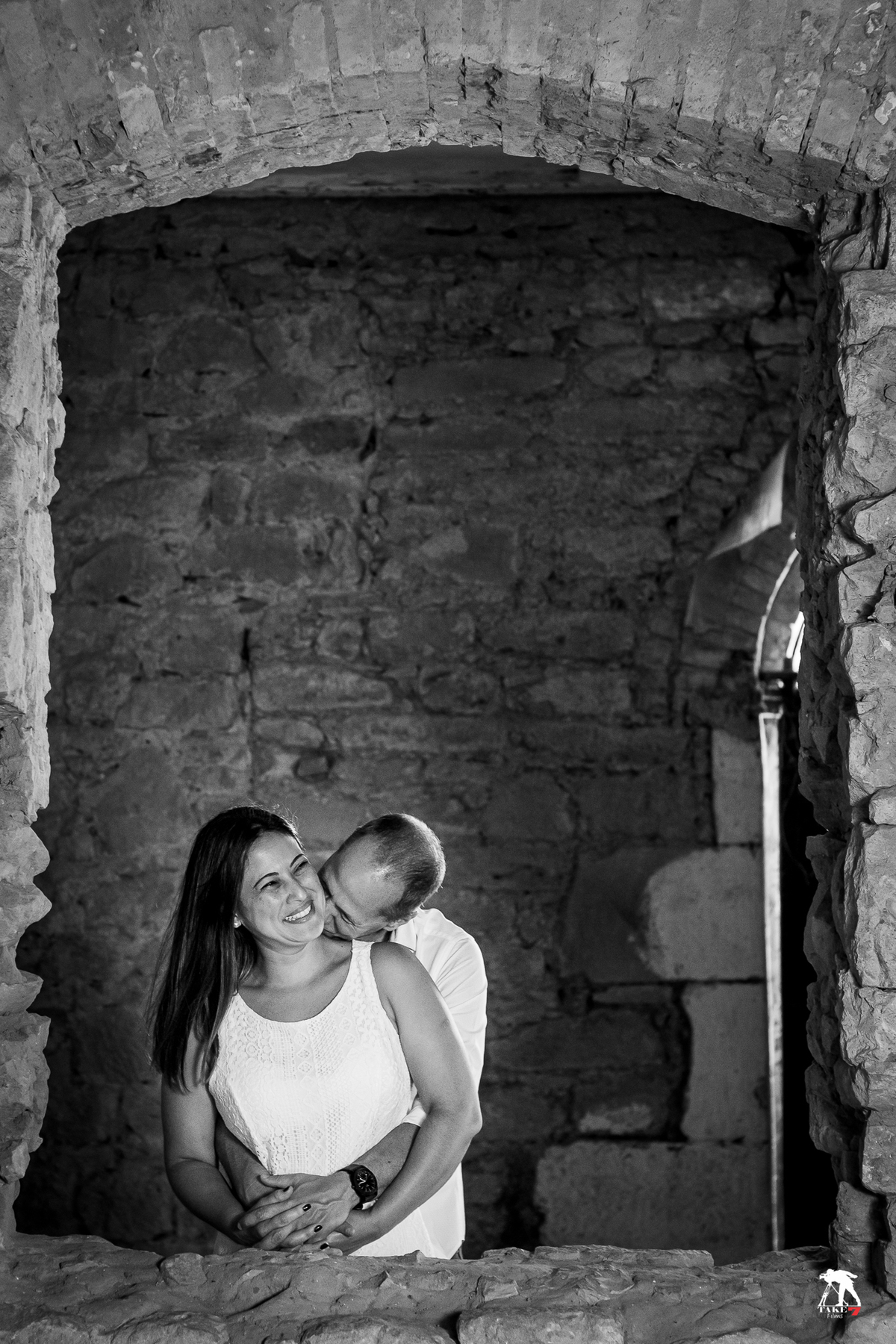 noivo beijando pescoço da noiva na janela 