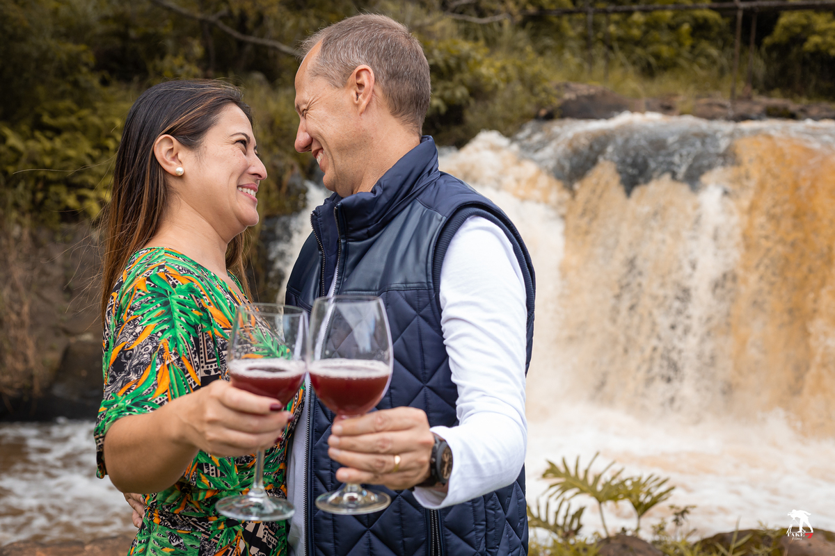 casal de noivos com taça de vinho no ensaio  com cachoeira de fundo 