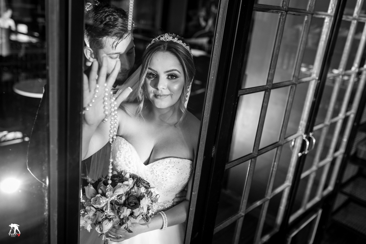 noiva e noivo pela porta de vidro em reflexo 