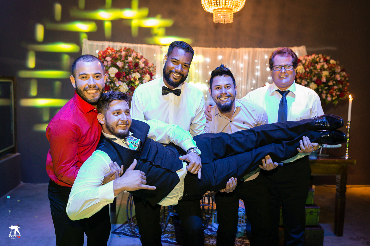 noivo nos braços dos padrinhos 