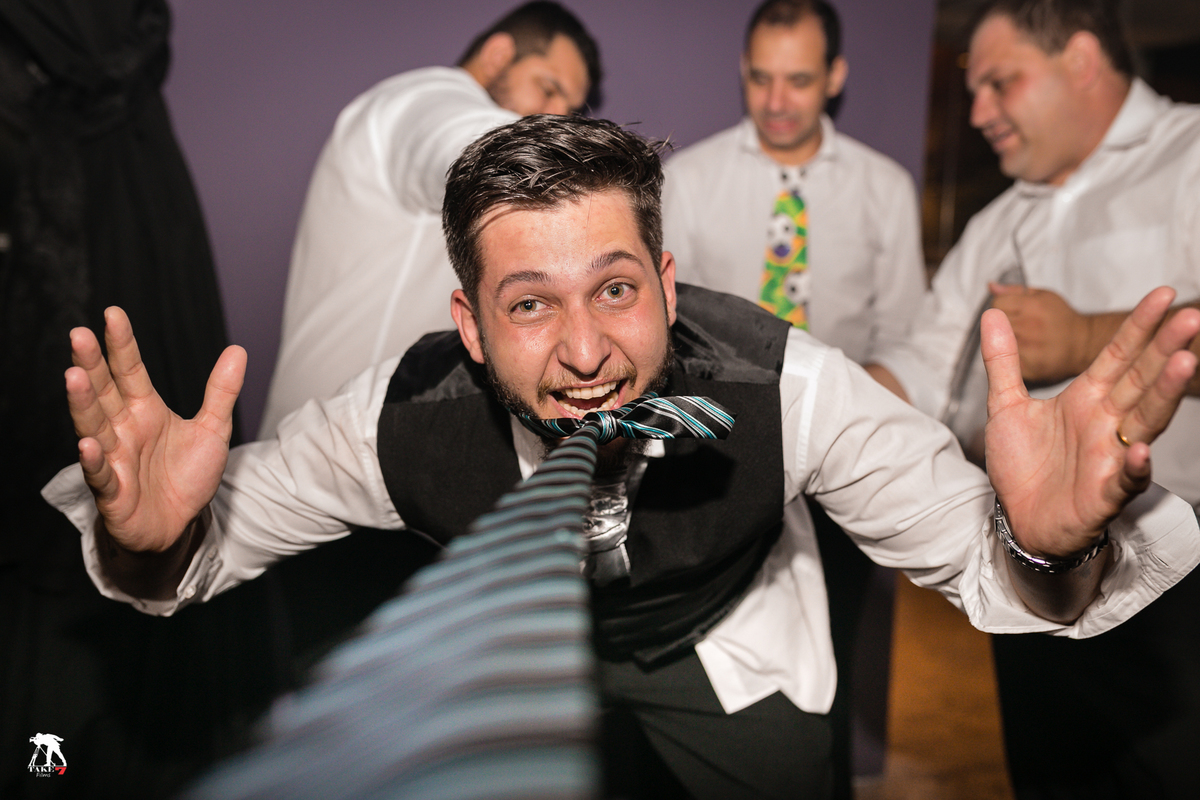 noivo mordendo a gravata enquanto cortam sua cueca durante a festa de casamento 