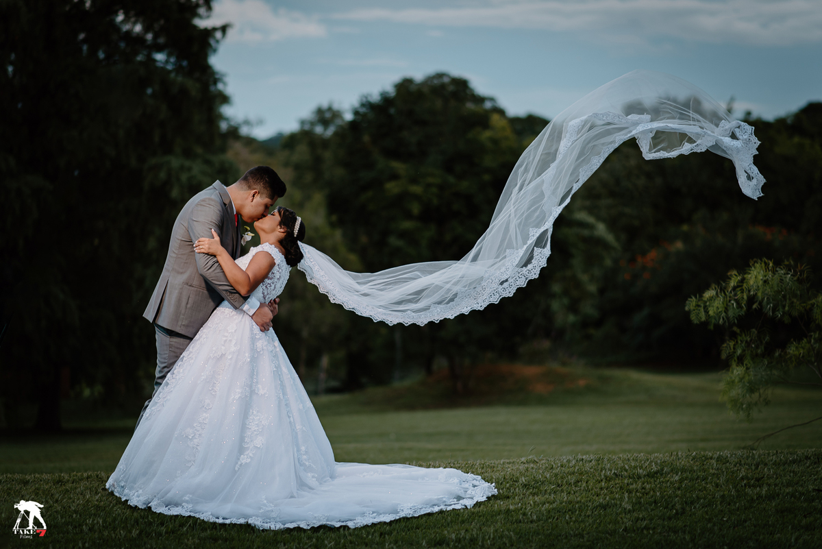 casal de noivos com véu da noiva voando