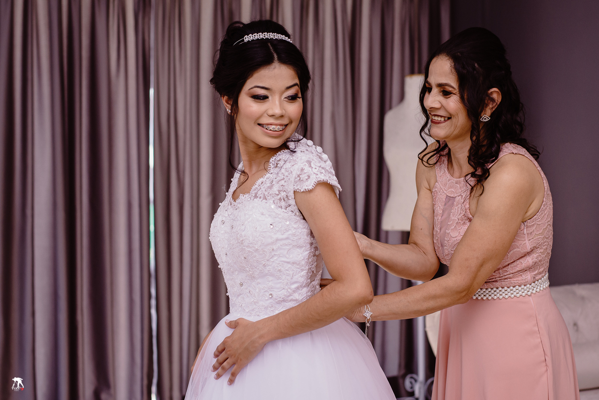 noiva colocando vestido com a mãe 