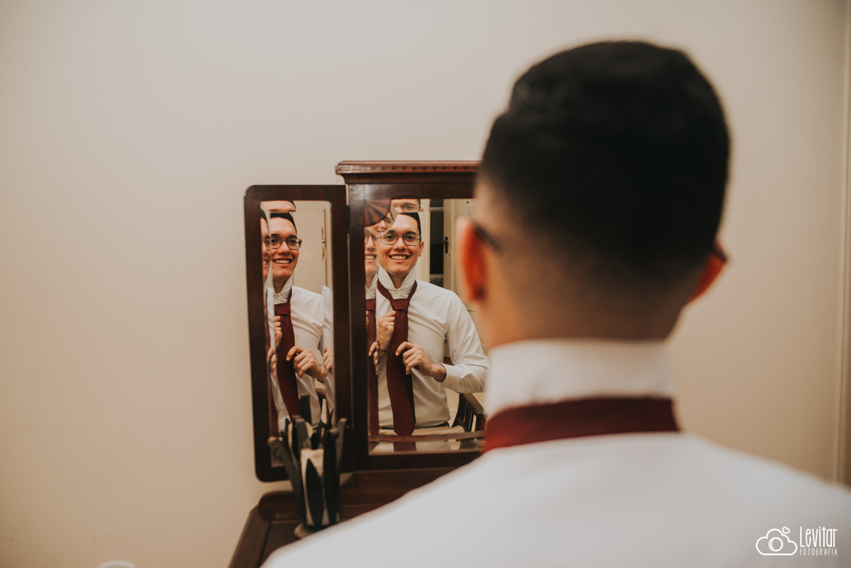 Noivo arrumando gravata olhando no espelho na Fazenda Marambaia 