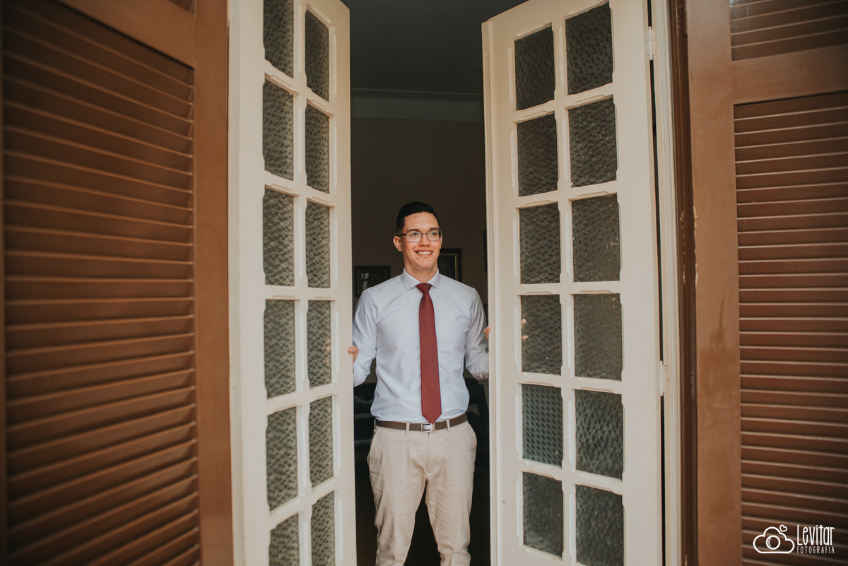 Noivo olha o local onde será a cerimônia através da porta da Fazenda Marambaia