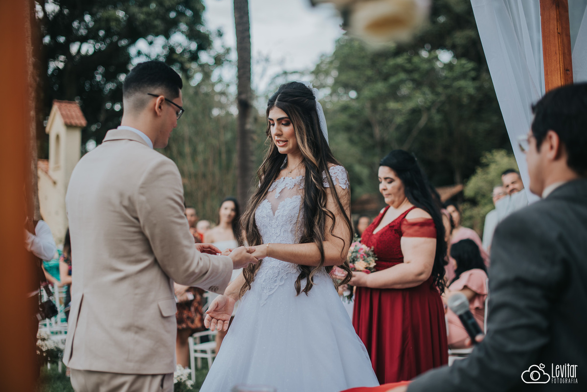 Noivo colocando aliança na mão da Noiva