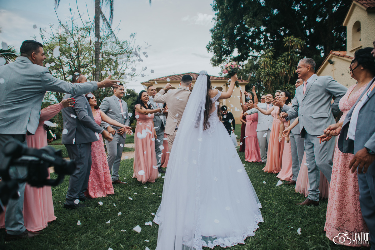 noivos saindo com pétalas sendo jogadas pelos padrinhos e madrinhas