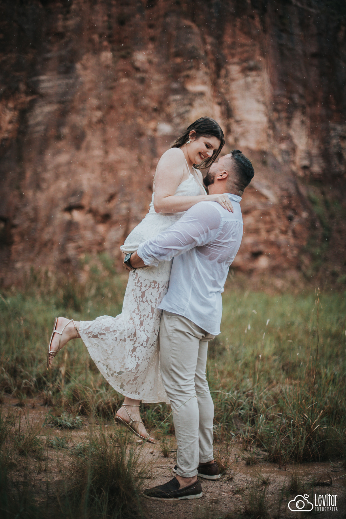 noivo com noiva no colo na chuva