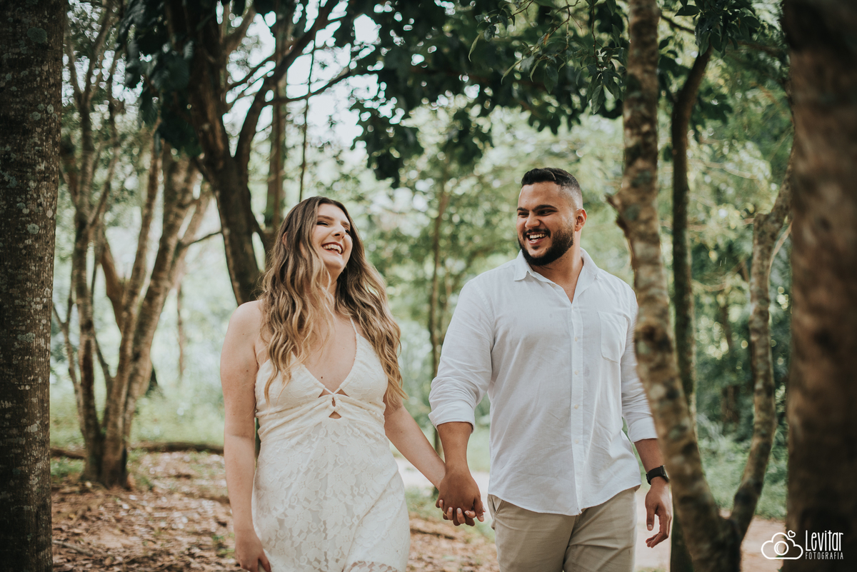 casal caminhando sorrindo entre árvores