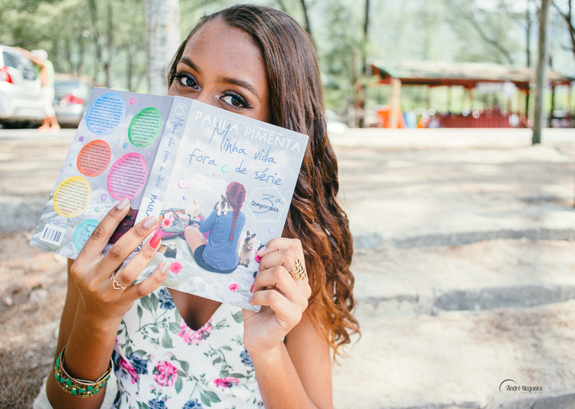 ensaio de 15 anos rj, debutante segurando o livro no rosto, praia de grumari, fotografo andre nogueira fotografia