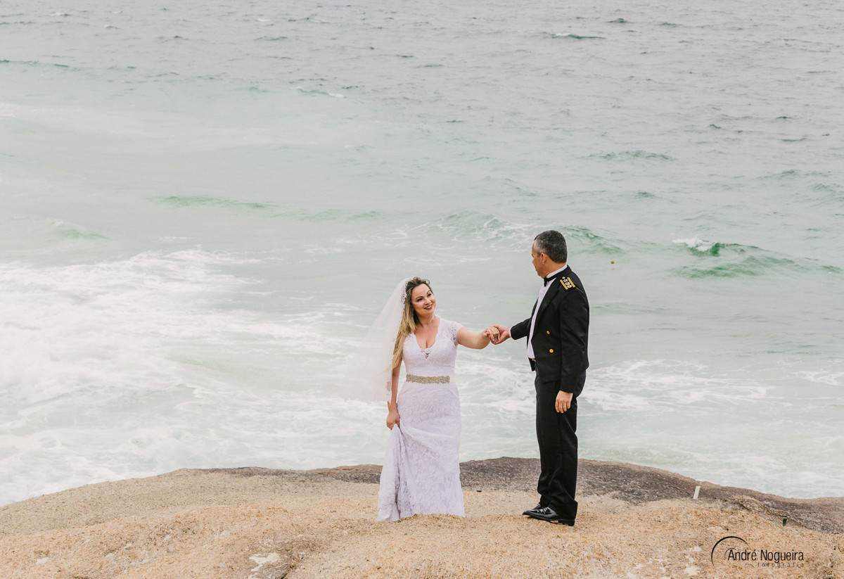 fotografia de casamento rj noivo ajuda a noiva subir a pedra do forte de copacabana  fotografado por andre nogueira fotografia fotografo de casamento rj durante o ensaio trash the dress