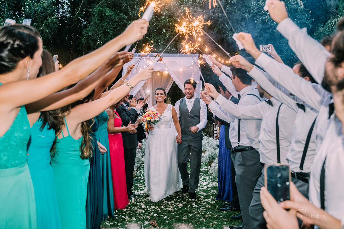 noivos passam pelo corredor formado pelos padrinhos, que estão segurando umas luzinhas, espaço coliseu vargem grande, andre nogueira fotografia fotografo de casamento rj