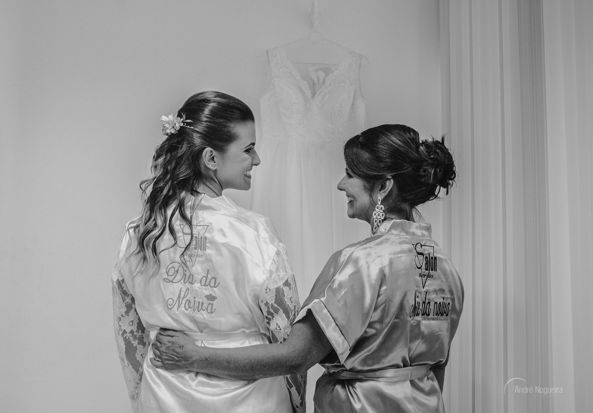 mãe da noiva abraçando a noiva durante o making of noiva rj em frente ao vestido da noiva no espaço coliseu vargem grande por andre nogueirafotografia