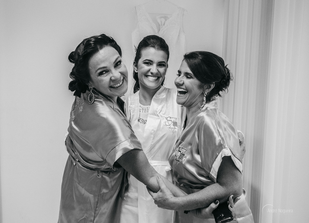 noiva abraçada com a sua mãe e sogra sorrindo durante o making of noiva rj para o andre nogueira fotografia  espaço coliseu vargem grande rj