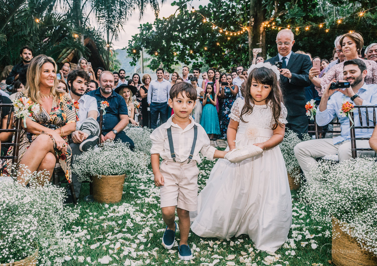 o pajem e a daminha entram pelo corredor com as alianças no jardim do espaço coliseu vargem grande durante a cerimonia de casamento