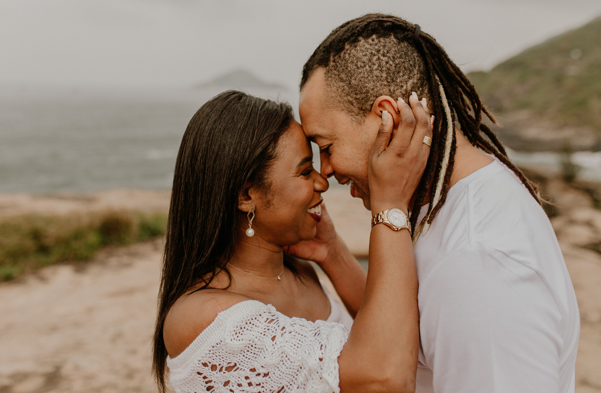ensaio casal ao ar livre na praia casal se olhando romanticamente durante o ennsaio fotografico pré casamento em cenários naturais do rio de janeiro