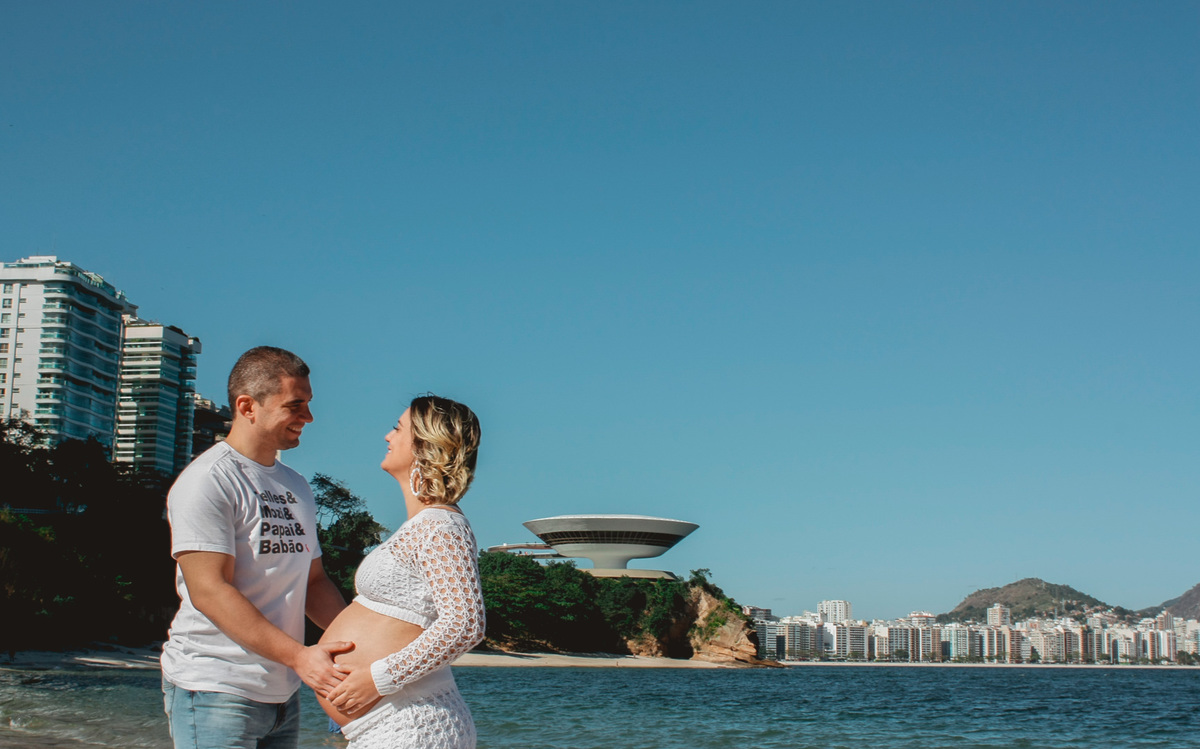 marido com a mão na barriga da sua esposa gestante com o museu da arte contemporânea ao fundo