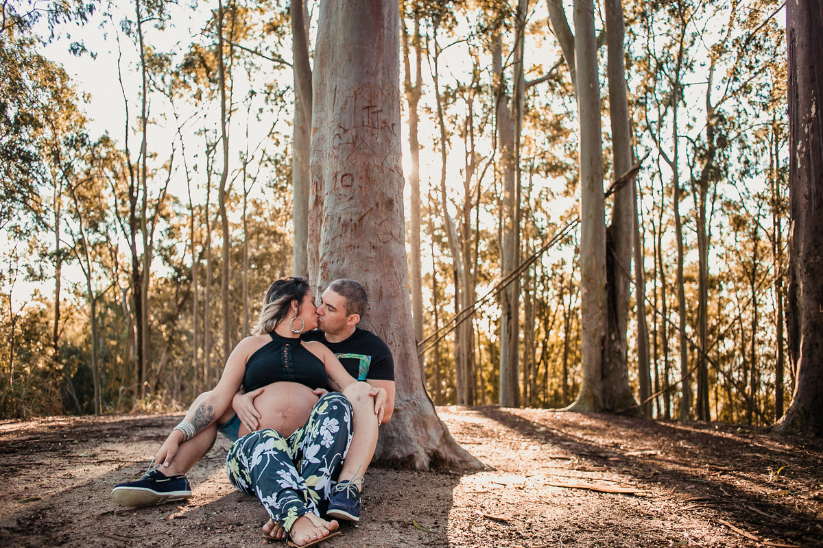 casal sentado no pé da árvore de eucalipto do parque da cidade e se beijando