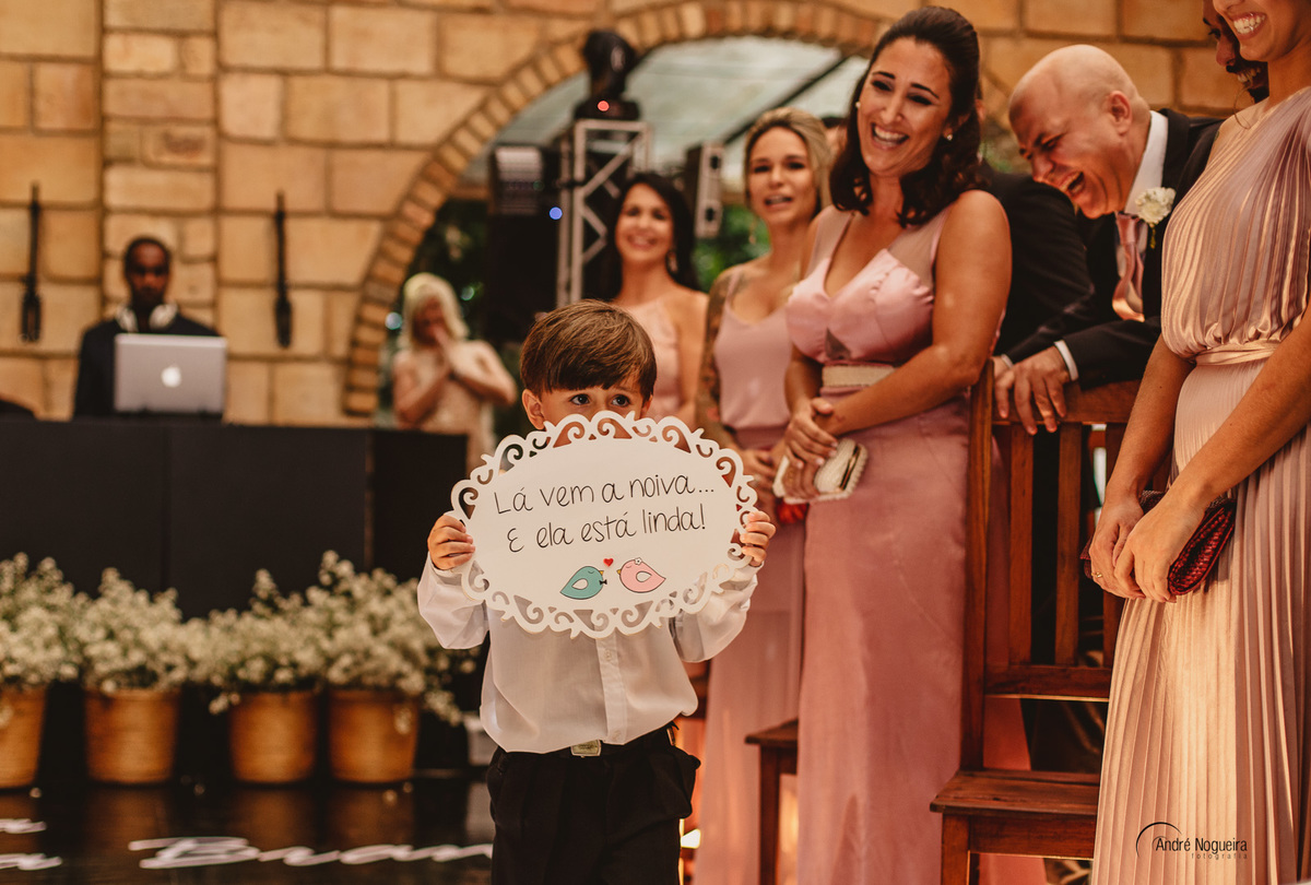 pajen entra na cerimonia de casamento no espaço coliseu eventos vargem grande segurando a placa de lá vem a noiva