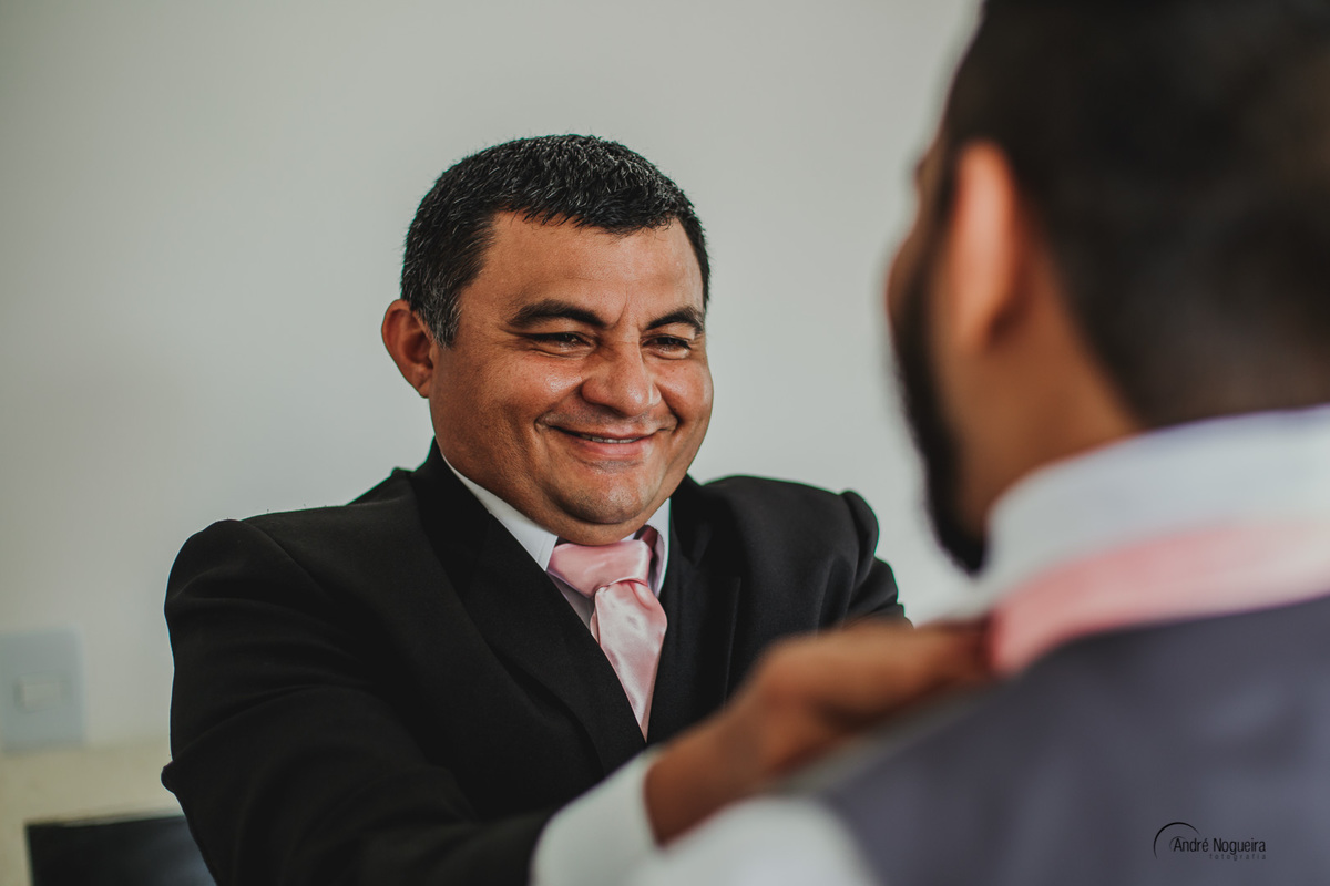 sorridente o pai do noivo ajuda seu filho a se arrumar durante o making of